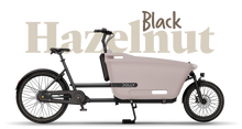 Load image into Gallery viewer, Product image of the Dolly Joy electric cargo bike with a black frame and cargo box. There is large text behind the bike describing its colour: Hazelnut Black.