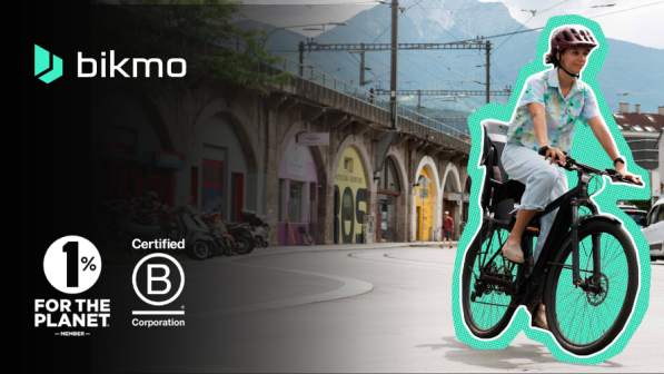 A photo of an urban setting with a woman cycling an electric bike, and the Bikmo logo overlaid on it. 