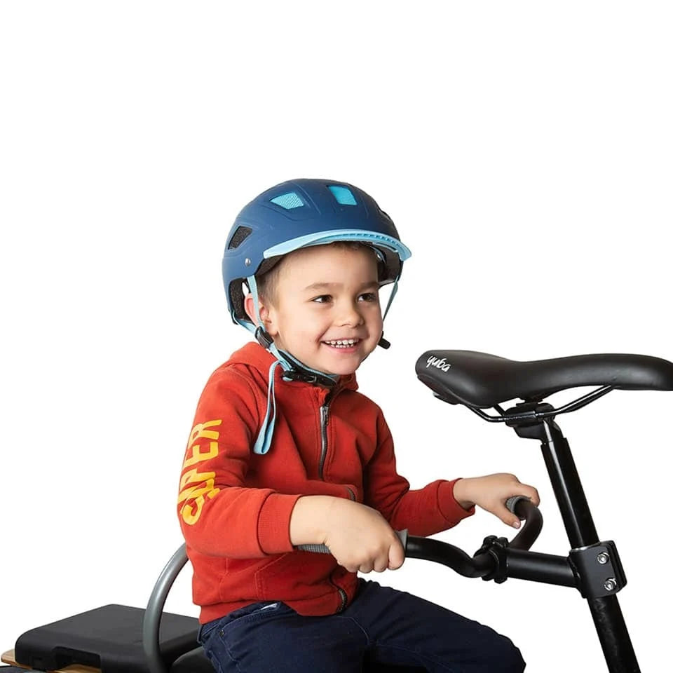 Child wearing a helmet seated on an electric cargo bike, holding Yuba hold-on bars mounted under the saddle for added safety.