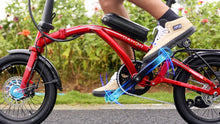 Load image into Gallery viewer, Person riding a red Dahon Curl electric bike with a blurred background
