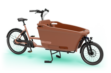 Load image into Gallery viewer, Product image of the Dolly Joy electric cargo bike with an orange frame and cargo box, seen from an oblique angle.

