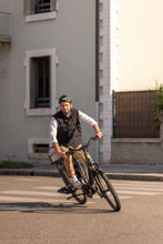 Load image into Gallery viewer, A lifestyle image of a man cycling a Yuba Boda Boda electric longtail cargo bike in an urban setting.
