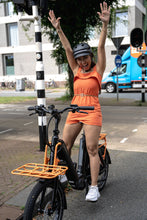 Load image into Gallery viewer, A lifestyle image of a woman cycling a BESV CPT 1.4 compact electric bike in an urban setting. 
