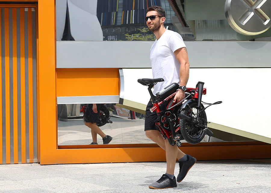 Man carrying a Dahon Curl folded electric bike in an urban setting