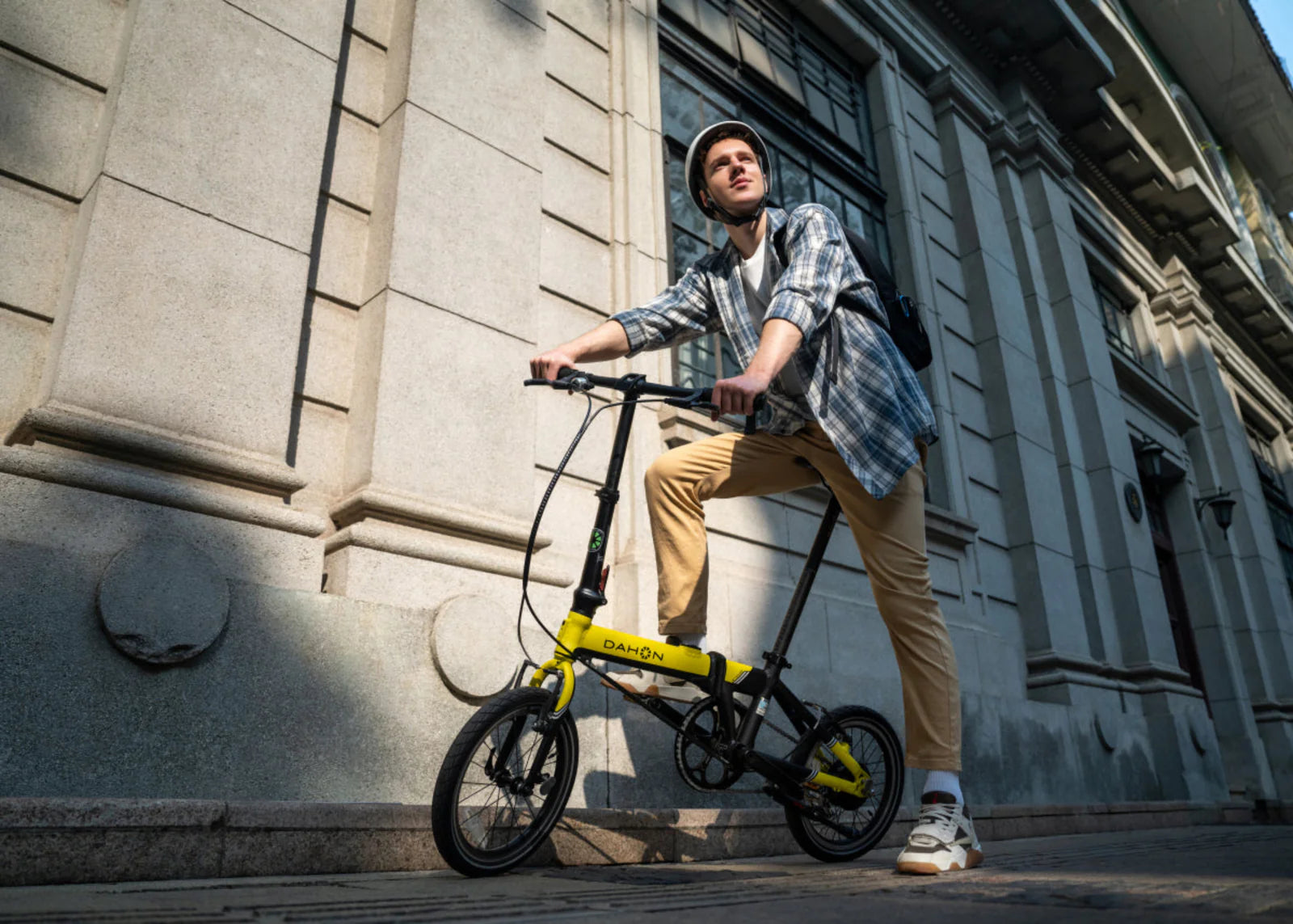 Man with a yellow and black bicycle in front of a building