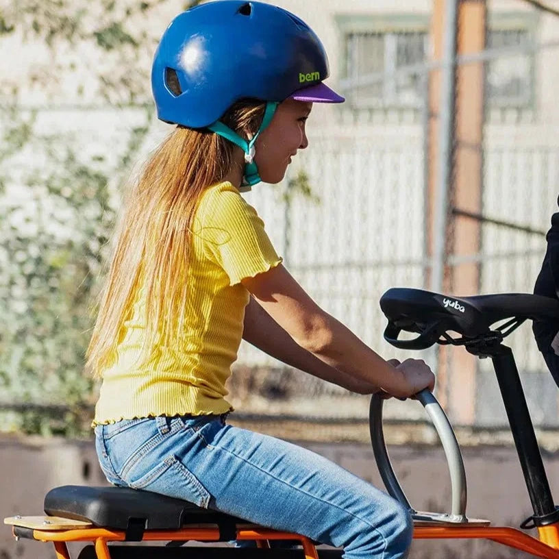 A photo of a child passenger on the back of a Yuba longtail cargo bike holding onto the Yuba Ring accessory.